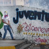 A masked anti-government protester holds a piece of metal during clashes with security forces in Caracas on Saturday. | AP