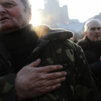 People sing the Ukrainian national anthem in Kiev\'s Independence Square on Monday. The country\'s acting government issued a warrant the same day for the arrest of ousted President Viktor Yanukovych, accusing him of mass murder. | AP