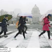 Here we go again: Students walk by the Diet building as snow falls in Tokyo on Friday. | KYODO
