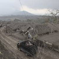 A truck carries animals for evacuation past houses covered with ash following an eruption of Mount Kelud in East Java, Indonesia, on Sunday. Indonesian volcano brings life as well as death