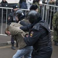 Russian police officers detain an opposition activist outside a court room in Moscow on Monday. Moscow court sends seven to prison for protest rally