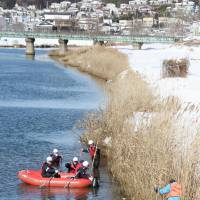 Kesennuma police officers on Tuesday search the banks of the Okawa River in Miyagi Prefecture for people still missing from the March 11, 2011, earthquake and tsunami. On the 11th of every month, police and volunteers search for the 234 residents of the city who remain unaccounted for. | KYODO
