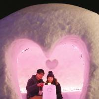A couple are seen through the heart-shaped entrance to a snow hut during the Kamakura Festival in Yokote, Akita Prefecture, on Friday. | KYODO
