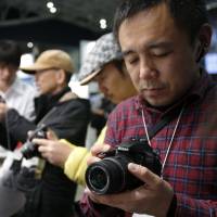 A visitor to the CP+ Camera and Photo Imaging Show in Yokohama inspects a Nikon Corp. D3300 digital single lens reflex camera Thursday. The show runs through Sunday. | BLOOMBERG