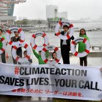 Members of environmental group Greenpeace display a banner and life preservers with the names of world leaders, during a protest over global warming held in front of the venue for a meeting of the Intergovernmental Panel on Climate Change in Yokohama on Sunday. | AFP-JIJI