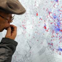 A visitor at the Center of the Tokyo Raids and War Damage in Koto Ward views a map Friday detailing how residents of the capital tried to flee U.S. air raids in 1945. | SATOKO KAWASAKI