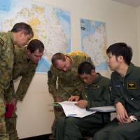 Australian military officers discuss a plan with Maritime Self-Defense Force Lt. Cmdr. Takayuki Kanemori during a briefing on the search for Malaysia Airlines Flight MH370 on Thursday at a Royal Australian Air Force base in Bullsbrook, Western Australia. | AFP-JIJI