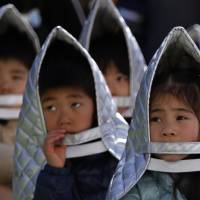 Kindergartners take part in a quake evacuation drill in Chiyoda Ward, Tokyo, on Tuesday. | REUTERS