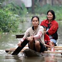 Residents paddle through a flooded village on the southern Philippine island of Mindanao on Jan. 13 following cataclysmic rainfall. | AFP-JIJI