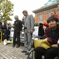 Hideki Sato (center), the leader of an aid group for Minamata disease victims, speaks after the Kumamoto District Court rejected the claims of five of eight unrecognized victims Monday. | KYODO