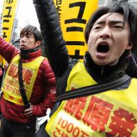 Falling out: Nuclear workers and their supporters shout slogans as they raise their fists in front of the headquarters of Tokyo Electric Power Co., operator of the stricken Fukushima No. 1 nuclear power plant, during a rally in Tokyo on March 14. | AFP-JIJI