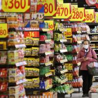 A customer browses through a riot of sale price signs at a Seiyu GK supermarket in Tokyo on March 13. | BLOOMBERG