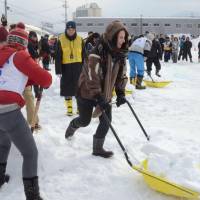 Participants scoop and carry snow in an international competition on snow shoveling held in Otaru, Hokkaido, in January. | KYODO