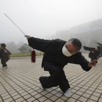 Wearing a face mask to guard against air pollution, a man exercises on a hazy morning in Fuyang, in China\'s eastern province of Anhui, on Wednesday. | REUTERS