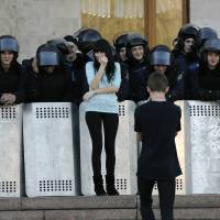 A young man takes photos of his girlfriend in front of a line of Ukrainian riot policemen guarding the regional administration building following a pro-Russian rally in central Donetsk on Sunday. | REUTERS