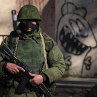 An armed man, believed to be a Russian soldier, stands near a Ukrainian military base in Simferopol, the capital of the semiautonomous Crimea region, on Monday. | REUTERS