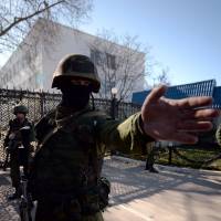 A pro-Russian soldier stands outside the headquarters of the Ukrainian Navy in the Black Sea port city of Sevastopol on Monday. | AFP-JIJI