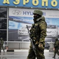 Unidentified armed men patrol Simferopol airport in Ukraine\'s Crimea region Friday. | AFP-JIJI