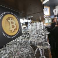A sign telling customers that the digital currency bitcoin is accepted as payment is displayed behind the counter in the Old Shoreditch Station cafe in London on March 7. | BLOOMBERG