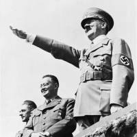 German Chancellor Adolf Hitler smiles as he salutes a huge crowd at a sports meeting in Breslau, Poland, July 31, 1938, in which Sudetic Germans participated. Behind Hitler are Konrad Henlen, pro-Nazi Czechoslovakian politician (left) and Ernst Kundt, Deputy Chief of the Sudetic German Party. | AP