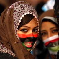 A Libyan anti-government protester with her face painted in the colors of Libya\'s former national flag takes part in a gathering in the city of Benghazi in February 2011. | AFP-JIJI