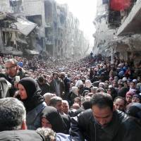 Residents of Syria\'s besieged Yarmouk refugee camp, south of Damascus, crowd a destroyed street during a food distribution drive on Jan. 31. U.N. investigators said Tuesday they had enough solid proof of war crimes committed by both sides in the Syrian civil war to prepare any indictment. | AFP-JIJI