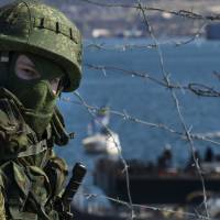 A Russian soldier guards a pier where two Ukrainian naval ships are moored, in Sevastopol, Ukraine, on Wednesday. | AP