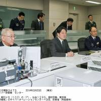 Defense Minister Itsunori Onodera (center) sits Monday in the operations center of the ministry\'s new cyberspace defense unit. | KYODO
