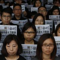 Editorial staff from the daily Ming Pao hold the front page of their newspaper with a headline about former editor Kevin Lau, who was assaulted and injured during a protest outside the Ming Pao\'s offices in Hong Kong on Thursday. The former editor of the Hong Kong newspaper whose abrupt dismissal in January sparked protests over press freedom is in critical condition after being hacked Wednesday by an assailant with a meat cleaver, police said. | AP