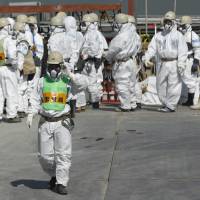 Workers congregate by the No. 4 reactor of the crippled Fukushima No. 1 power plant in the town of Okuma, Fukushima Prefecture, on March 6, 2013. | AP