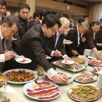 Attendees to a pro-whaling event held Tuesday in Tokyo help themselves to a buffet featuring whale meat.  | AP