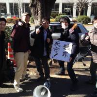 Victorious: Activists (left to right) Ryo Onda, Yosuke Oda, Yuichi Utsumi, Makoto Masui and Taku Arai gather around a placard reading \"Innocent: a desperately fought defense!\" The  Tokyo High Court recently upheld their acquittal on charges under the Law for the Punishment of Acts of Violence in a case that became a rallying point for students across Japan. | COURTESY OF BUNKA RENMEI