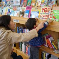 Pick and choose: A mother helps her child select an English-language book from a selection that has become a big draw card for Iwakura Public Library. | NOZOMI IKEDA