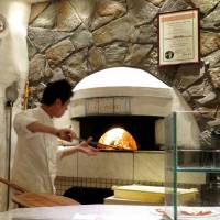 Eating Italian: A pizzaiolo works the furnace at Pizzeria Tonino. | ROBBIE SWINNERTON