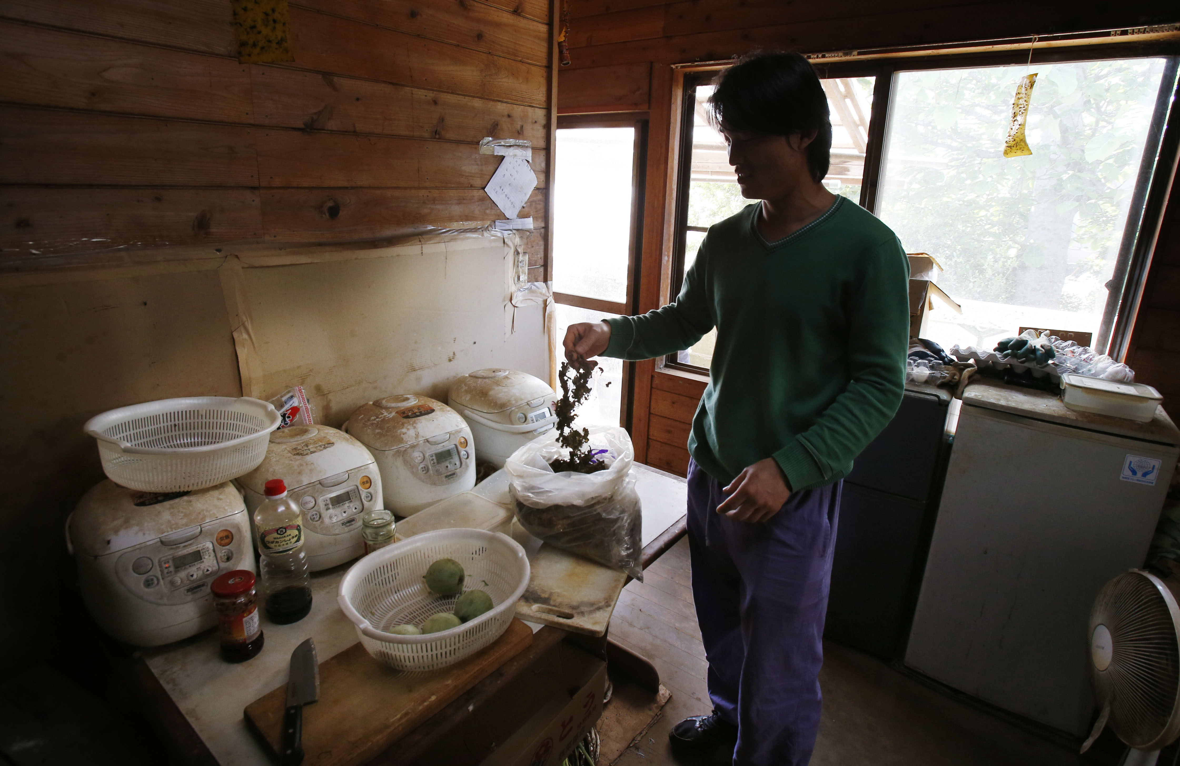 Wang Zhigan, a 31-year-old Chinese laborer, prepares a lunch at his dormitory in Hokota, Ibaraki Prefecture, last May. | AP
