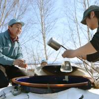 Brewers in the town of Biei, Hokkaido, sample sake Wednesday that was aged under the snow. | KYODO