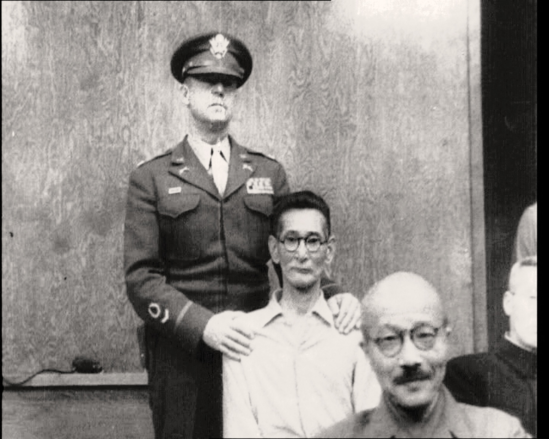 Slap happy: Shumei Okawa (center) is restrained  after slapping former Prime Minister Hideki Tojo (front) on the head on May 3, 1946, at the International Military Tribunal for the Far East. | www.britishpathe.com