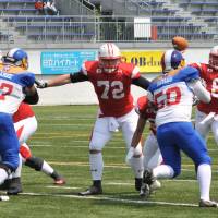 Perfect performance: Japan starting quarterback Shun Sugawara throws a pass while Philippines defenders Marc Anthony Patiag (59) and Juan Paolo Suarez (97) give pressure during the first quarter of the Asian qualifier for the 2015 IFAF World Championship. Sugawara completed 4 of 4 passes, including two touchdowns, in Japan\'s 86-0 triumph on Saturday. | HIROSHI IKEZAWA