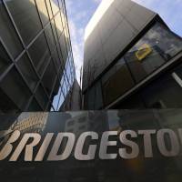 The Bridgestone Corp. logo is displayed outside the company’s Bridgestone Institute of Global Training in Tokyo on Feb. 18. The company is among two dozen Japanese businesses hit hard by recent bid-rigging and price-fixing investigations in the United States. Fines, snitching fuel U.S. antitrust blitz against Japan firms
