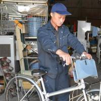 Junji Nagayama holds the handlebars of a Qjo bike.  | CHUNICHI SHIMBUN