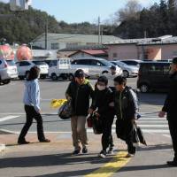 Children walk to Furumichi Elementary School, which reopened on April 7 in the Miyakoji district in the city of Tamura, Fukushima Prefecture. The shopping facility, which opened the day before, is seen in the background. Evacuees still wary of returning