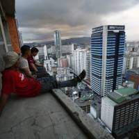 A group of men take in the view of Venezuela\'s capital after salvaging metal on the 30th floor of the \"Tower of David\" in central Caracas on Feb. 3. | REUTERS