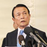 Finance Minister Taro Aso answers questions from reporters in Washington on Thursday. | KYODO