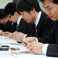 Newly hired employees of Mitsubishi Pencil Co. learn how to sharpen pencils with a knife as part of the firm\'s welcoming ceremony at its head office in Shinagawa Ward, Tokyo, on Tuesday. The event was first held in 2008 so new hires could familiarize themselves with the company\'s products. | SATOKO KAWASAKI