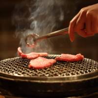 Slices of \"wagyu\" (Japanese beef) are grilled in a restaurant operated by Meat Companion Co. in Tokyo on March 24. | BLOOMBERG