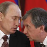 Russian President Vladimir Putin (left) speaks with Rosneft President Igor Sechin during a signing ceremony at the Kremlin in Moscow last July. On Monday, the United States imposed sanctions against seven Russian government officials and 17 companies linked to the president, including Sechin. | REUTERS