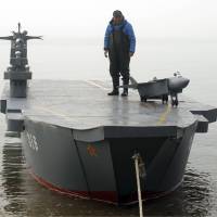 Retiree Wen Yuzhu stands on his homemade aircraft carrier in Qingdao, in east China\'s Shandong province, on April 2. The 80-year-old spent months building the model to fulfill his grandson\'s wishes. | AP
