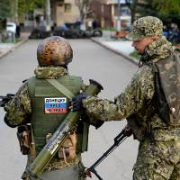 Armed men wearing military fatigues show off a sticker reading \"Donetsk don\'t listen to Kiev\" during a pro-Russian rally Friday in the eastern Ukrainian city of Slovyansk. | AFP-JIJI