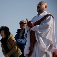A relative cries as a monk leads a prayer session Monday on South Korea\'s Jindo Island for victims of a ferry that sank last Wednesday. | AFP-JIJI