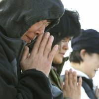 Relatives of passengers aboard the sunken ferry Sewol pray as they wait for their missing loved ones at a port in Jindo, South Korea, on Monday. | AP